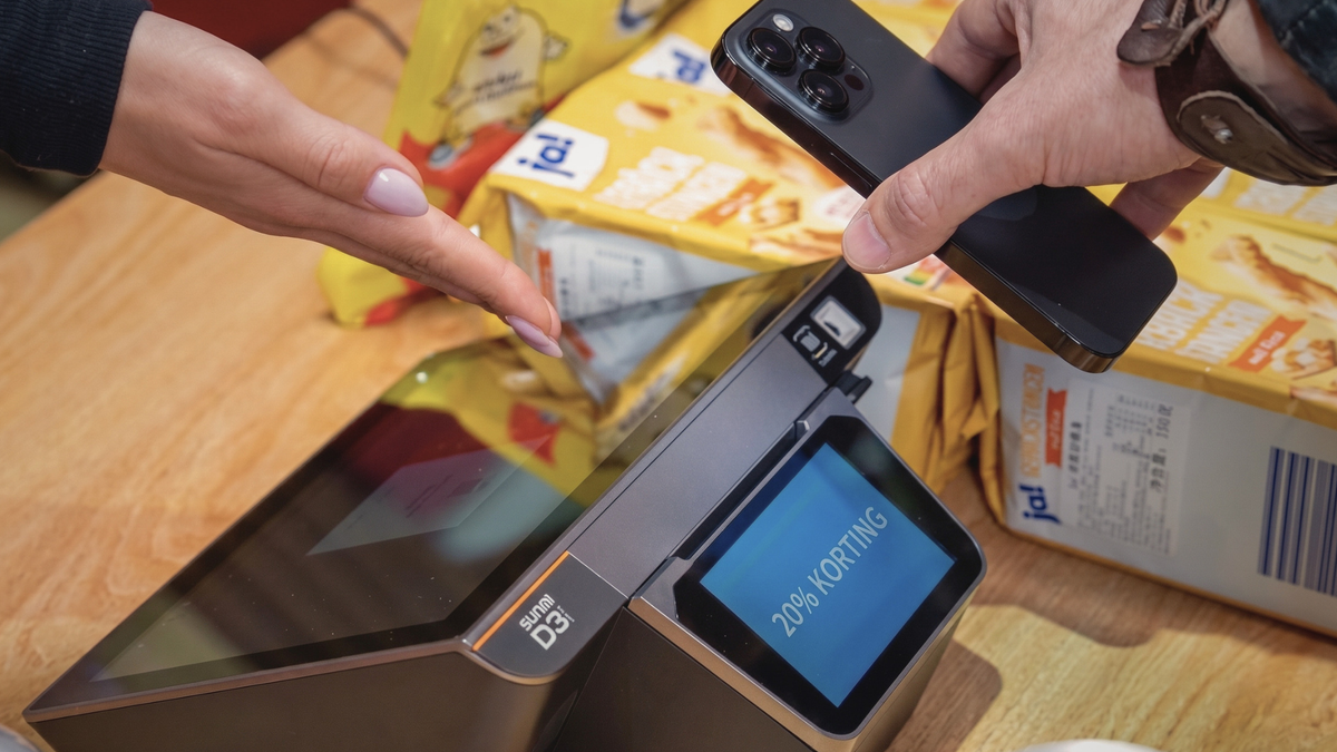Klant betaalt contactloos met de telefoon aan een kassasysteem met POSIFY retailsoftware, het klantendisplay toont 20% korting
