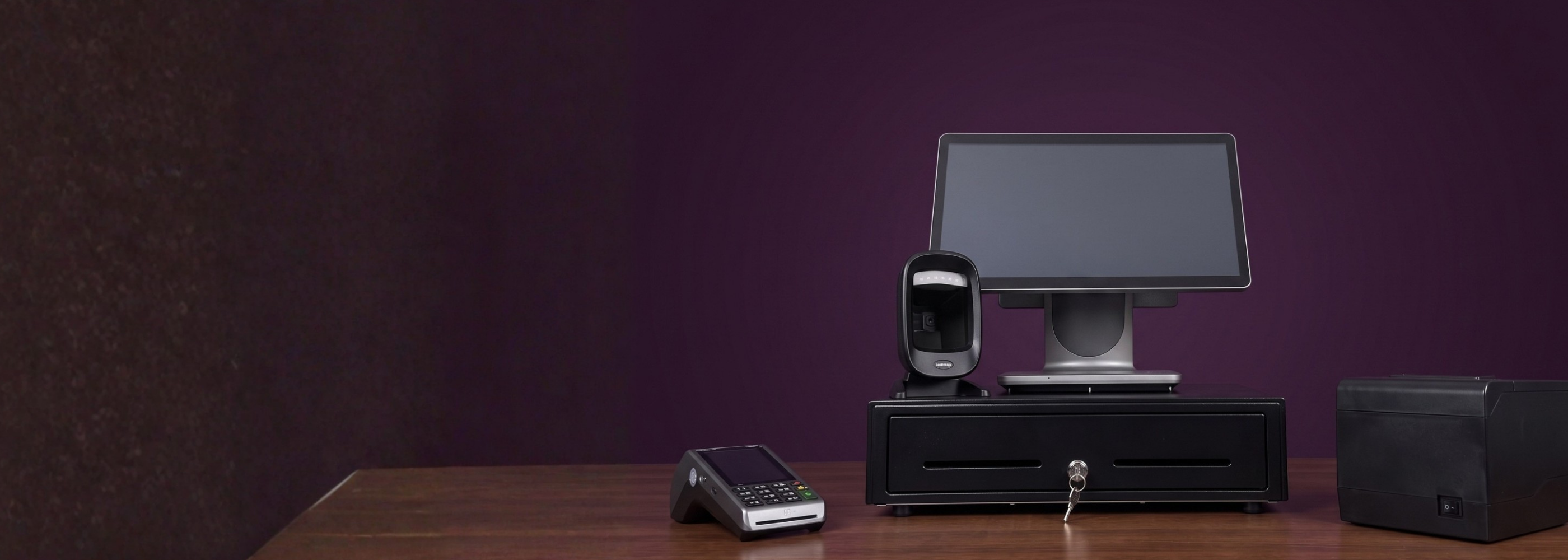 Kassaopstelling met touchscreen, scanner, kassalade, bonprinter en pinautomaat tegen een paarse wand