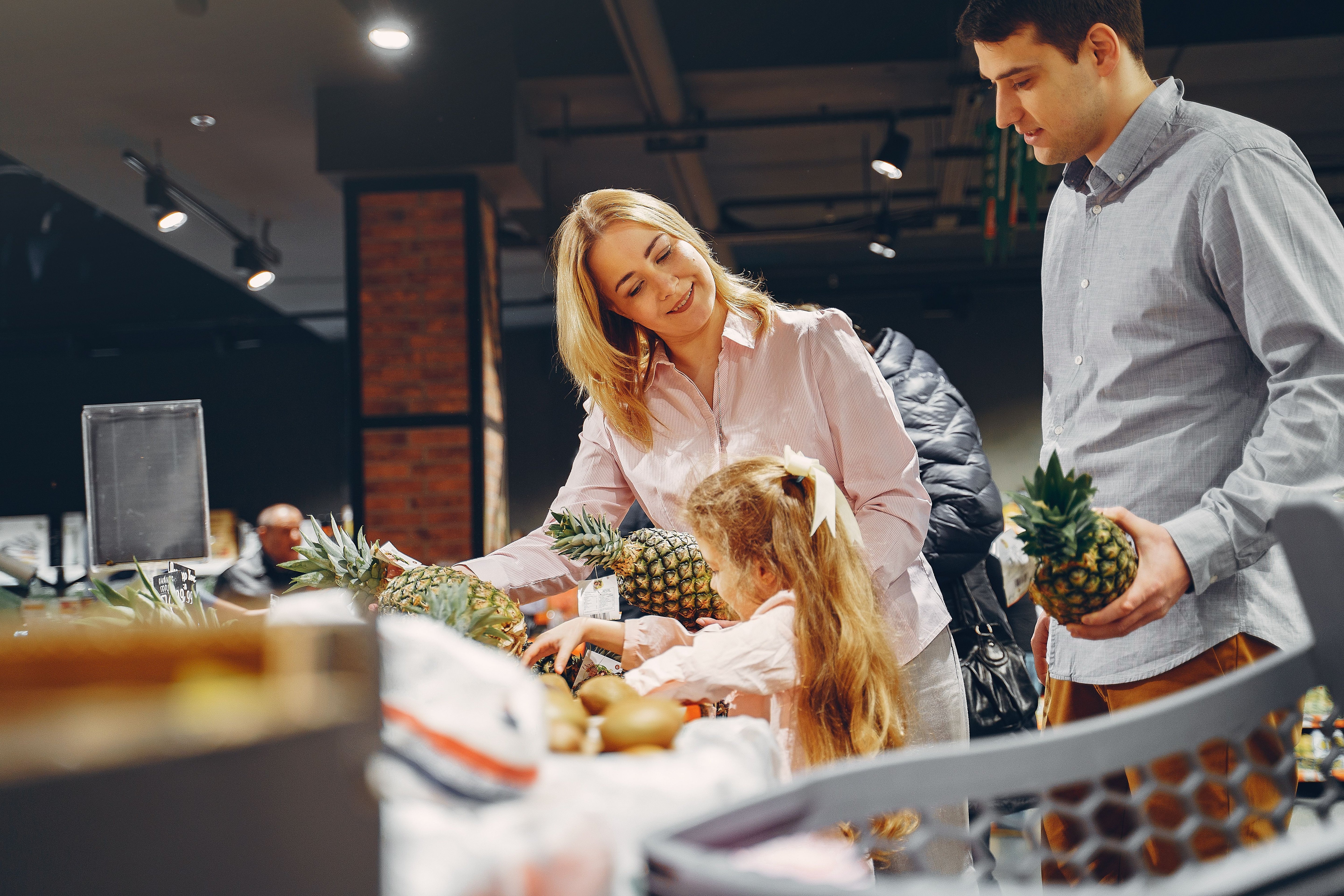 Gezin kiest een ananas uit bij de groente- en fruitafdeling van een supermarkt